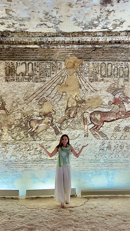Niloofar standing with open arms before a carved temple wall