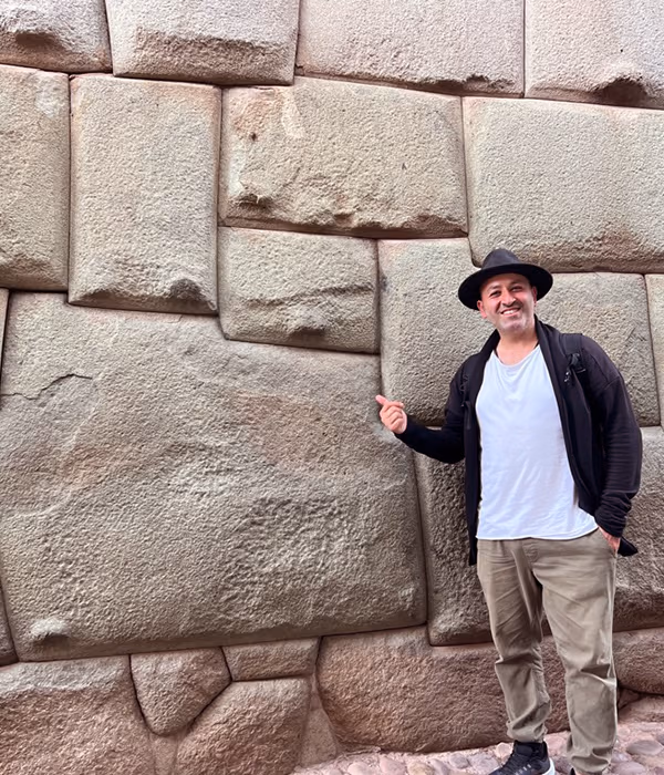 A man beside a wall of vast interlocking stones