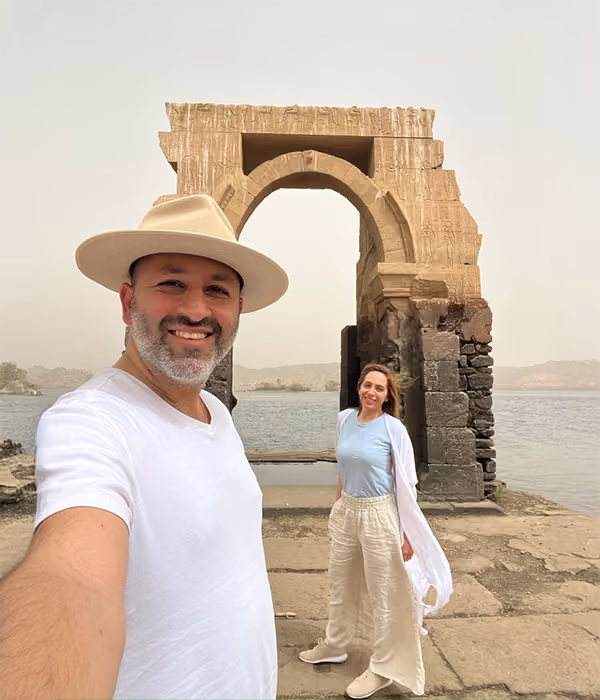 Two people beside an ancient stone arch